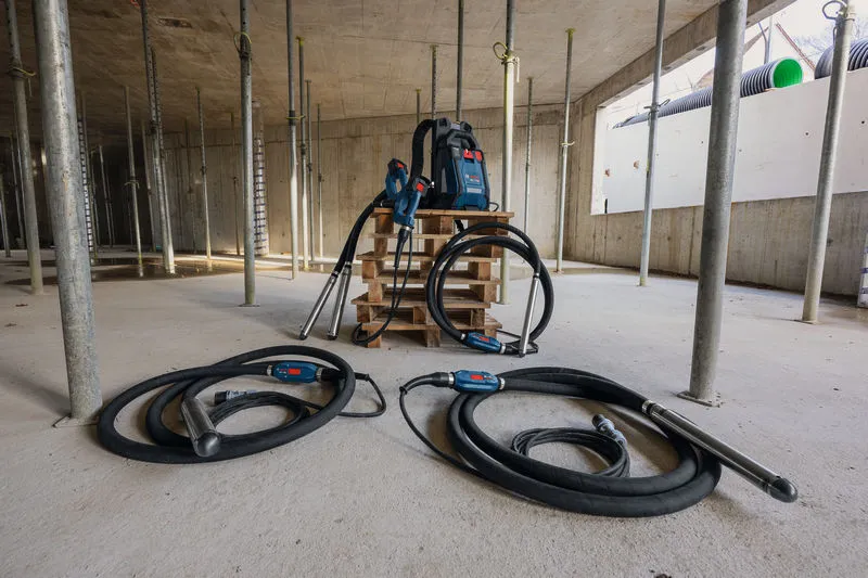 Palet üzerinde iki beton vibratörü ve bir sırt çantası tipi güç kaynağının bulunduğu şantiye.