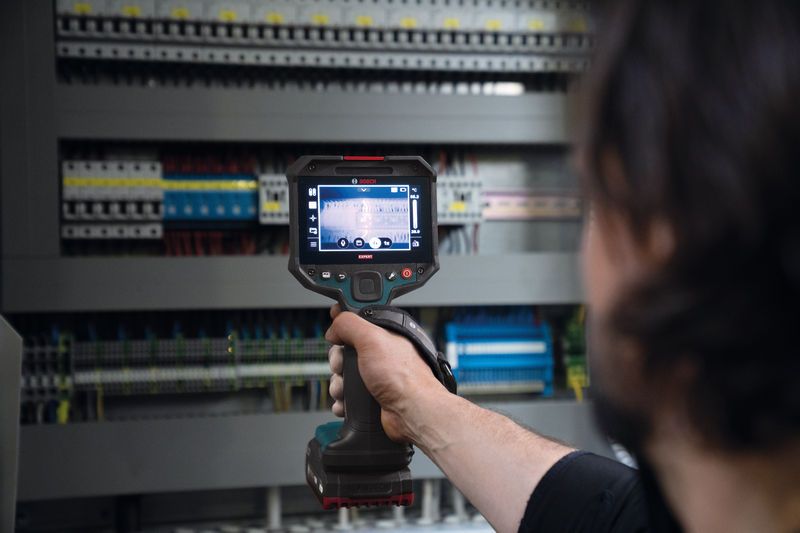 Bir kişi, bir elektrik kontrol panelini incelemek için termal kamera kullanıyor.
