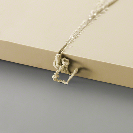 Excess material residue protruding from a drilled hole in a light-colored board.