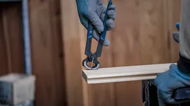 Person wearing safety equipment uses end cutting pliers to pull a nail from wood.