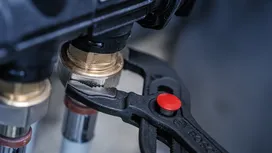Adjustable pliers tightening a brass pipe fitting.