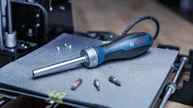 Electric screwdriver on a workbench next to three screwdriver bits.