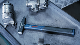 Metal hammer on a workbench beside engine parts.