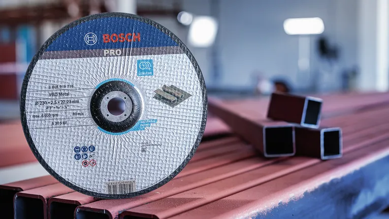 Disco de corte apoyado sobre tubos metálicos en un taller industrial.