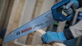 Una persona, equipada con material de seguridad, corta madera con una sierra de mano.