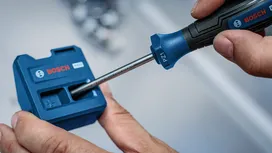 Una persona utiliza un destornillador para insertar una broca en un accesorio de herramienta azul.
