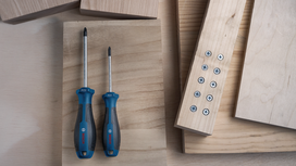 Dos destornilladores sobre una superficie de madera junto a tablones unidos con tornillos.