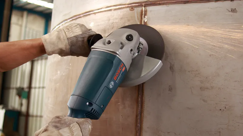 Una persona que usa equipo de seguridad muele una superficie metálica utilizando una amoladora angular.