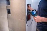 Una persona utiliza una cámara de inspección para examinar el interior de un panel de pared.