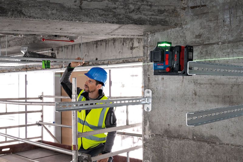 Una persona que usa equipo de seguridad alinea barras de metal utilizando una herramienta niveladora láser.