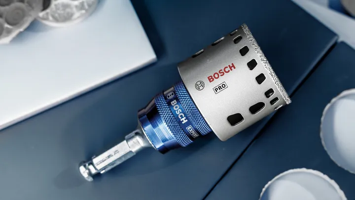 Sierra de corona de diamante colocada sobre una superficie azul para cortar con precisión agujeros circulares.