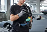 Una persona que usa equipo de seguridad aplica pulimento a una pulidora en un taller de automóviles.