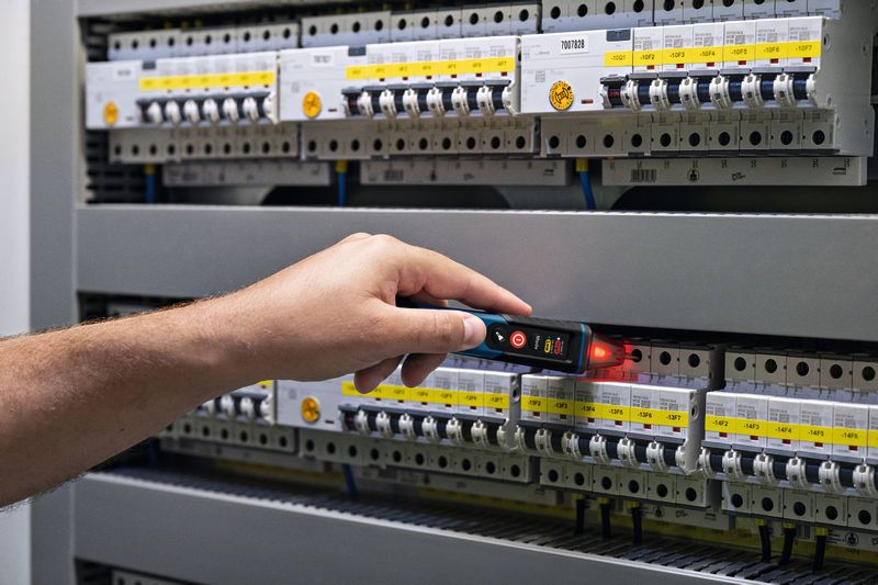 Persona probando un panel eléctrico con un comprobador de voltaje sin contacto.