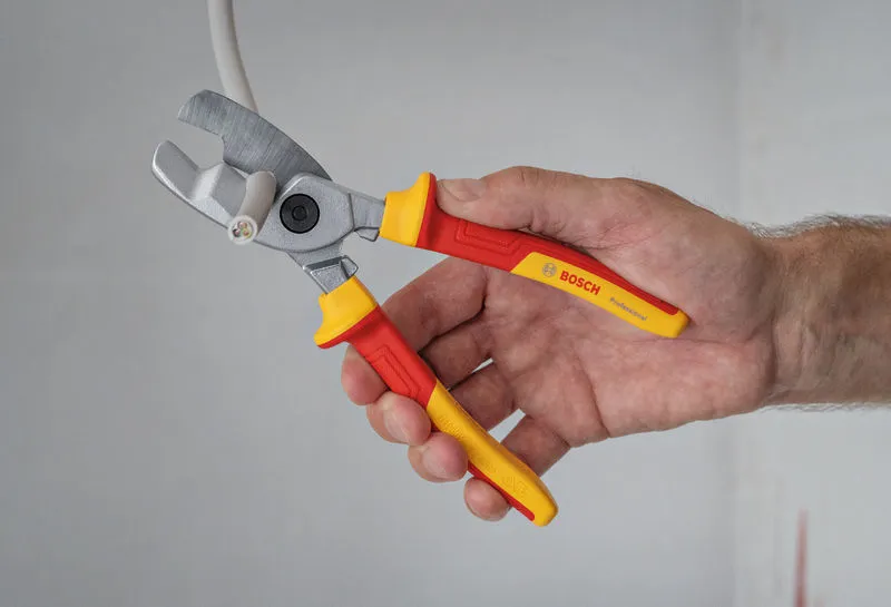 A person cuts an electrical cable using insulated pliers.