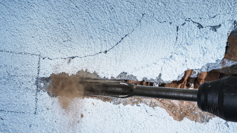 Rotary hammer chiseling a groove in a plastered wall.