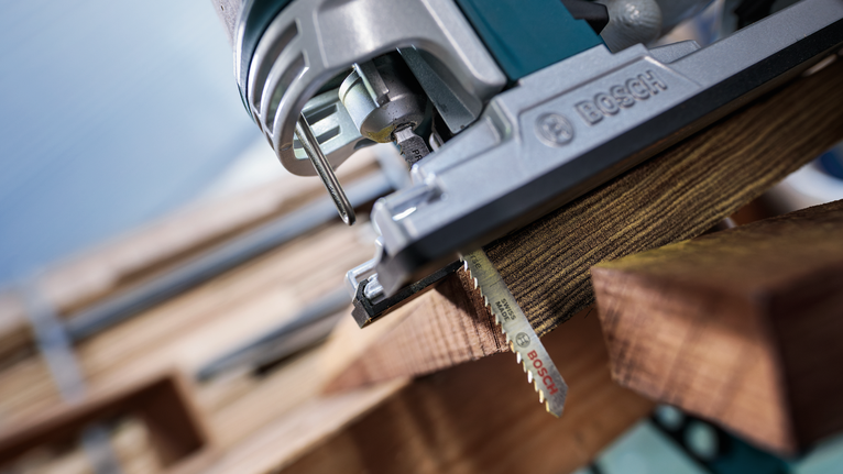 Jigsaw cutting through a piece of wood in a carpentry setting.