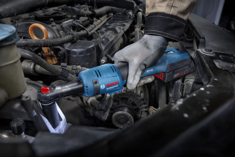 A person wearing safety equipment uses a cordless ratchet wrench to tighten a bolt in a car engine.