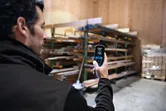 A person uses a thermo hygrometer to measure temperature and humidity in a lumber storage area.
