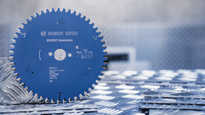 Circular saw blade standing upright on a metal checker plate surface.