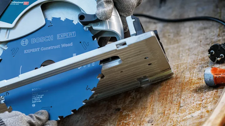 Person wearing safety equipment installs a circular saw blade into a power tool.