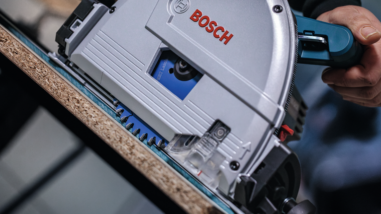 Person guides a circular saw to cut a wood board along a straight edge.